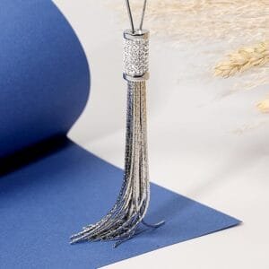 Collier sautoir femme argenté avec pendentif tassel en acier inoxydable présenté sur fond bleu