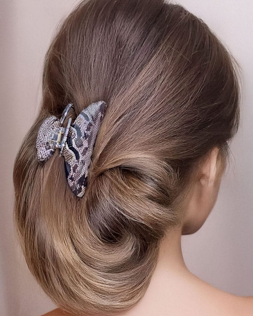 Femme de dos avec un chignon élégant maintenu par une pince cheveux épais ClawMeUp en motif python
