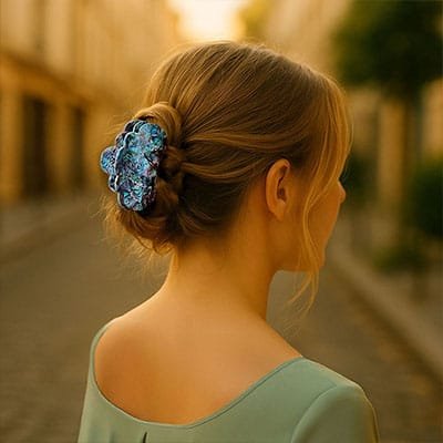 Femme élégante de dos dans une rue parisienne portant une pince à cheveux bleue florale ClawMeUp sur un chignon tressé