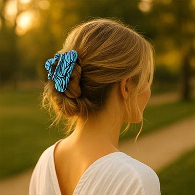 Femme de dos portant une pince à cheveux bleue motif zébré ClawMeUp dans un chignon bas, en extérieur