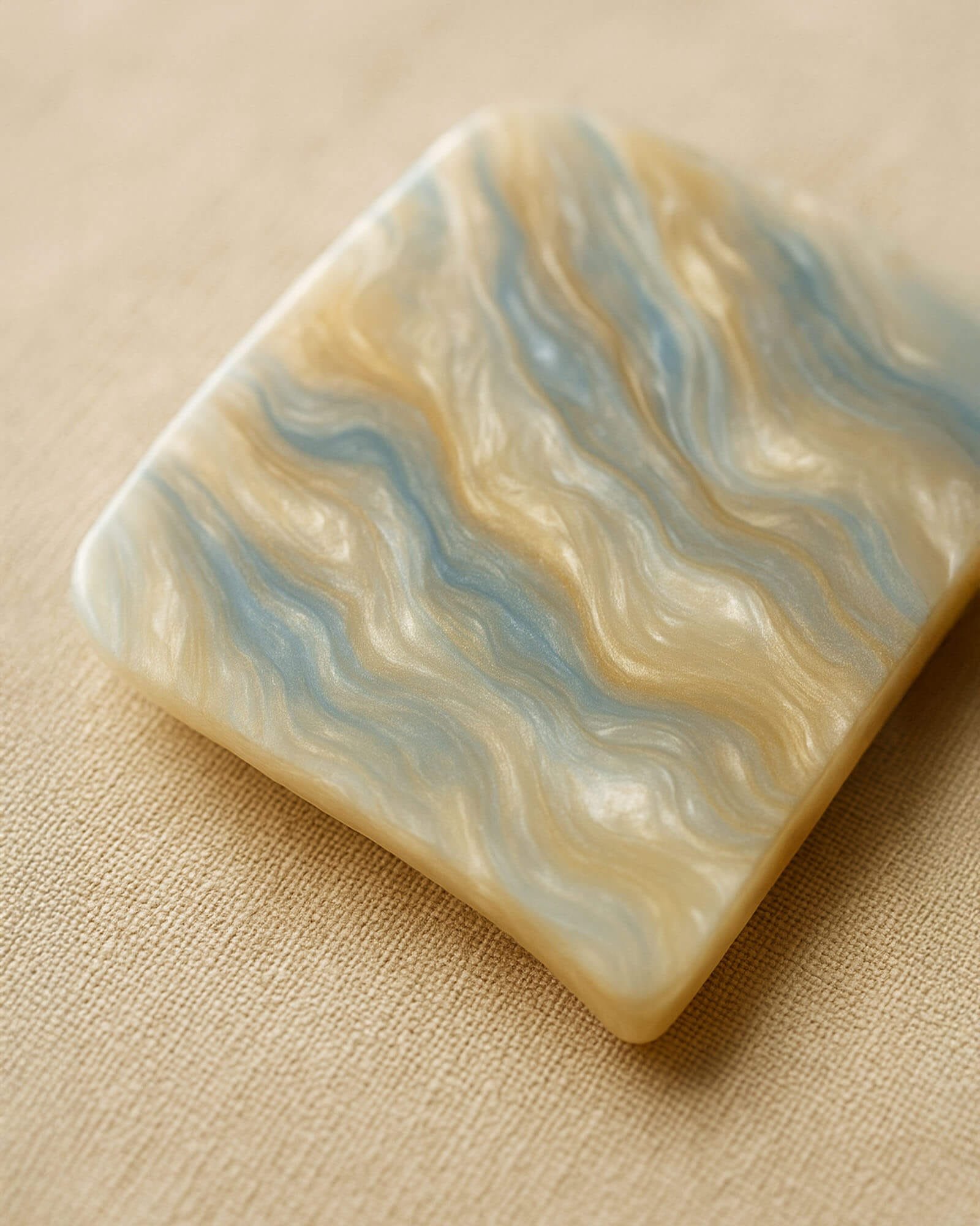 Macro de texture d’acétate de cellulose marbrée bleu et doré sur fond de lin beige, rendu premium