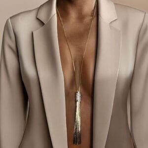 Collier long femme doré porté avec blazer beige, bijou raffiné à pampilles