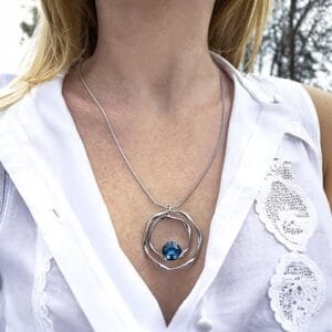 Collier pendentif femme argenté porté, avec pendentif cercle ajouré et pierre bleue