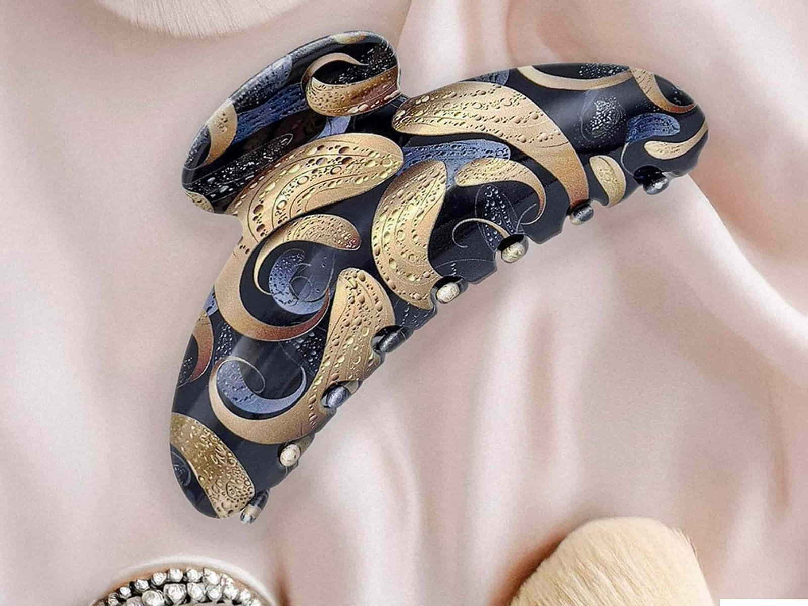 Pince à cheveux ClawMeUp en acétate premium posée sur un tissu beige élégant