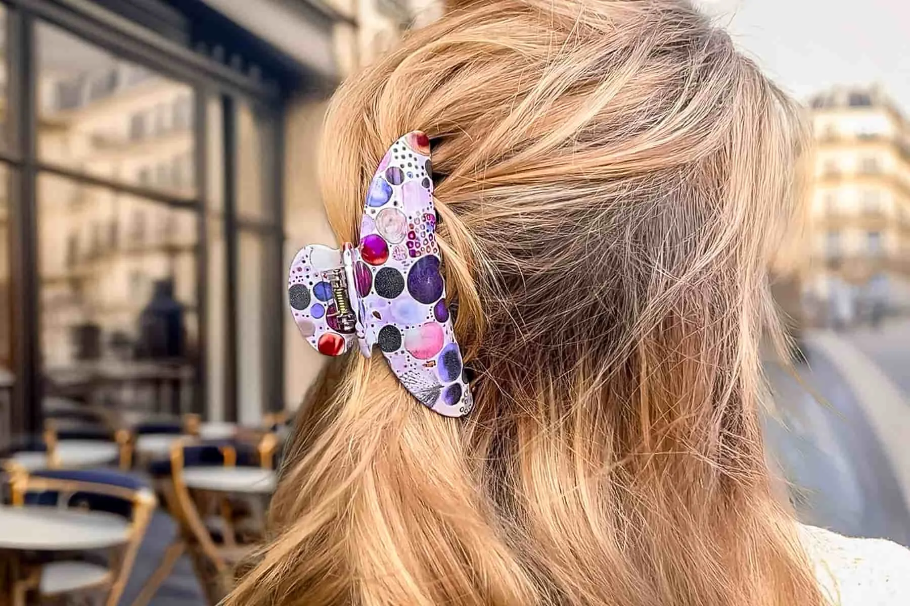Pince à cheveux ClawMeUp portée dans une coiffure élégante sur une terrasse parisienne