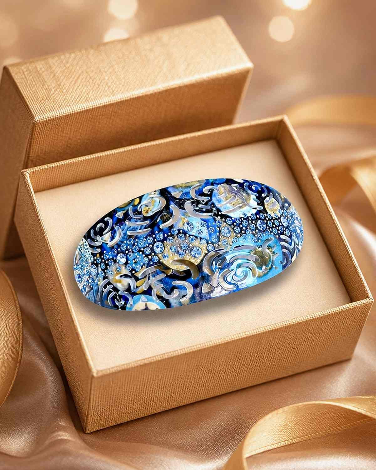 Pince à cheveux originale ClawMeUp impression UV noire et dorée présentée dans un écrin cadeau doré — accessoire cheveux luxe