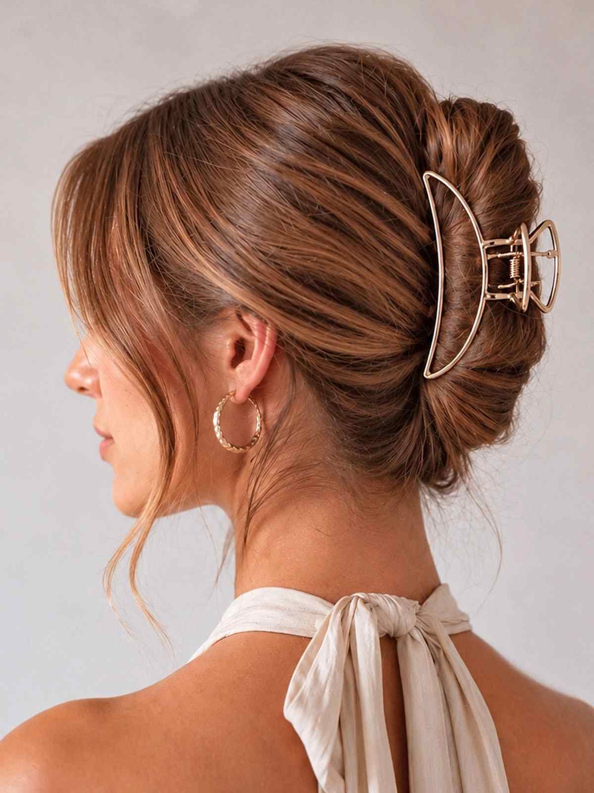 Femme de profil portant une pince crabe dorée en métal ClawMeUp dans un chignon élégant