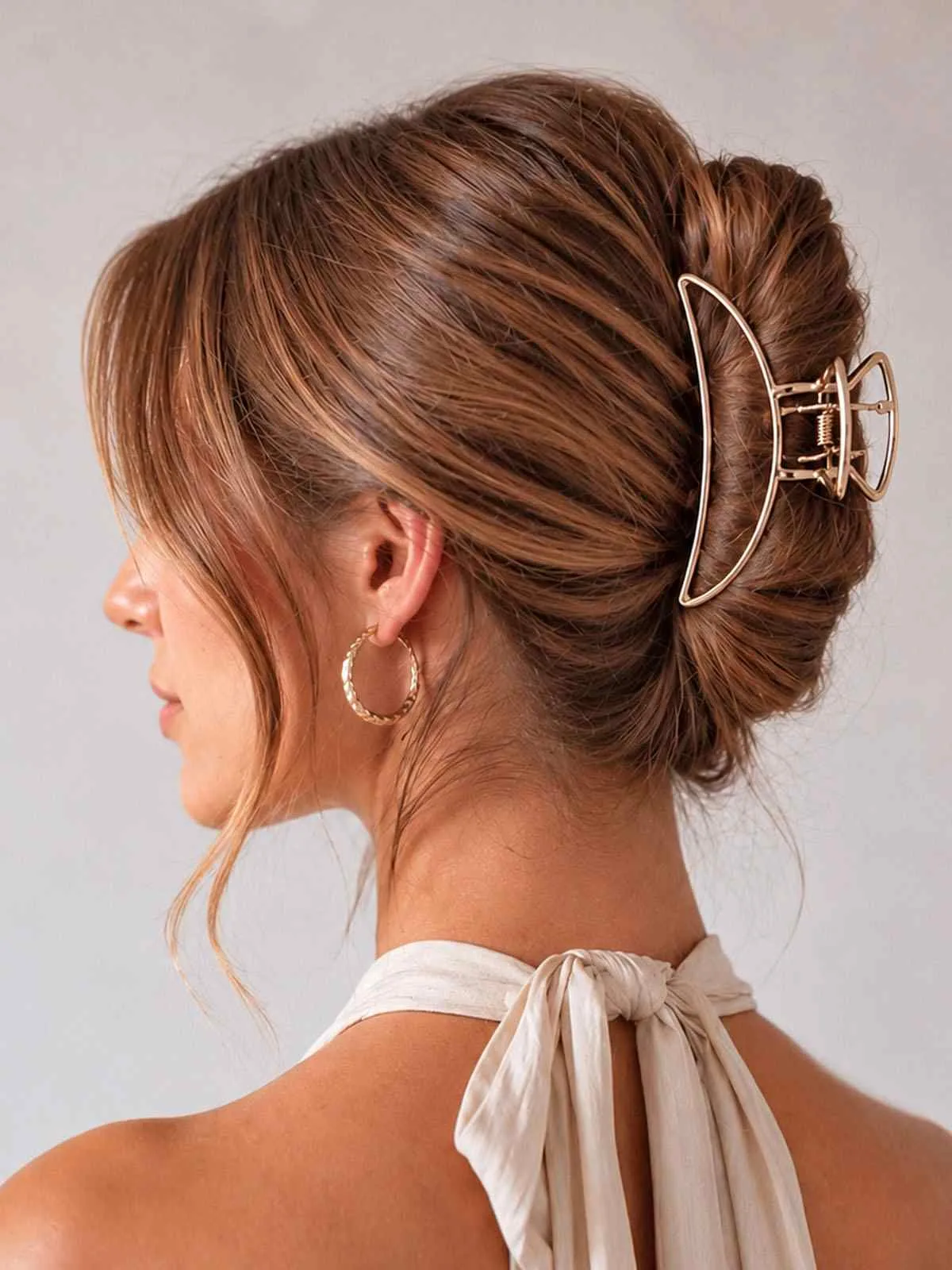 Femme de profil portant une pince crabe dorée en métal ClawMeUp dans un chignon élégant